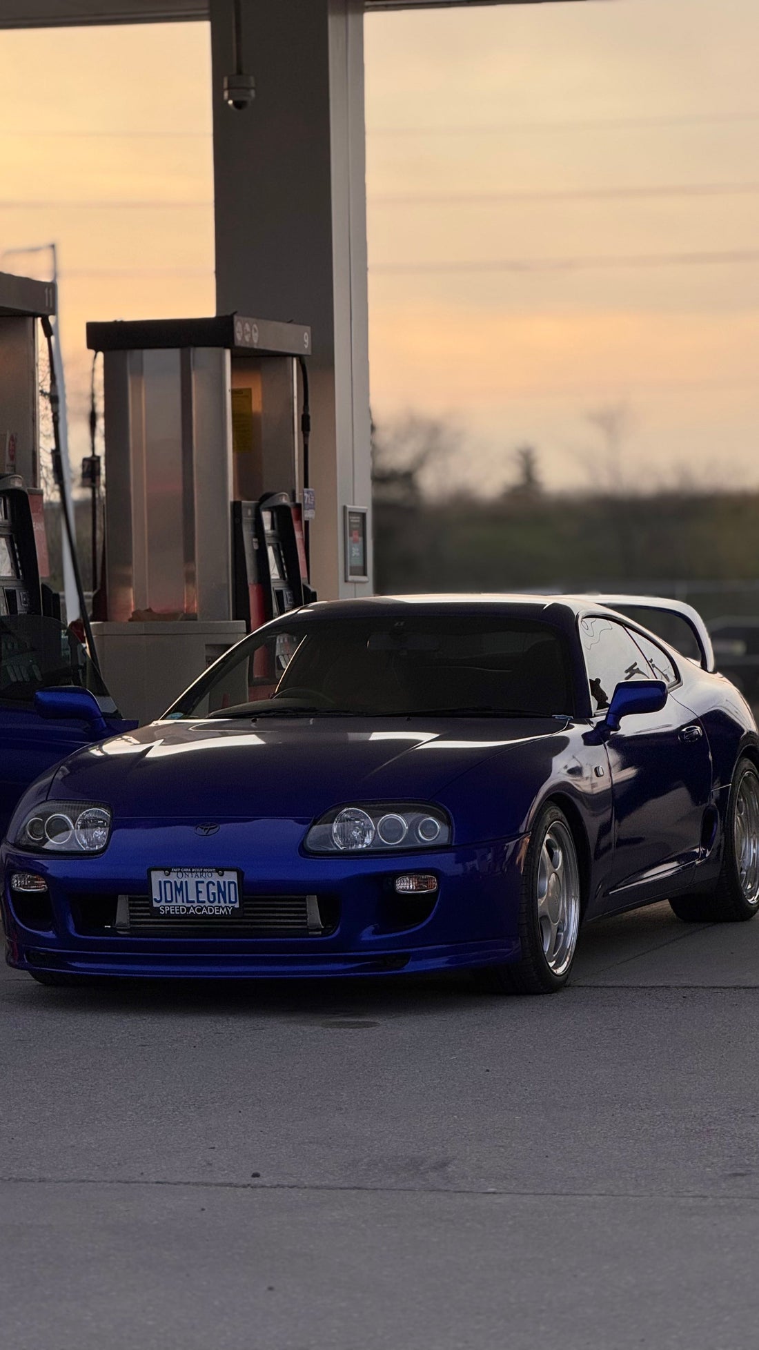 Blue 1993 Toyota Supra at gas station in evening.